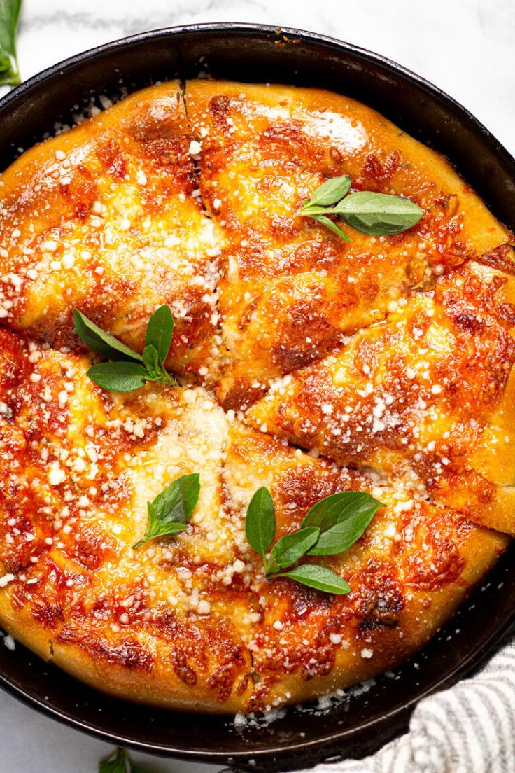 a pizza with cheese and herbs in a pan