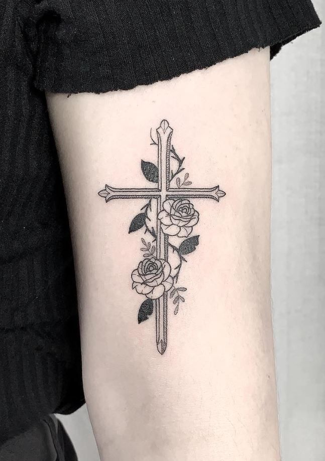 a cross tattoo with roses on the arm