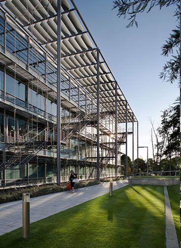 the building is very large and has lots of glass on it's sides, along with green grass