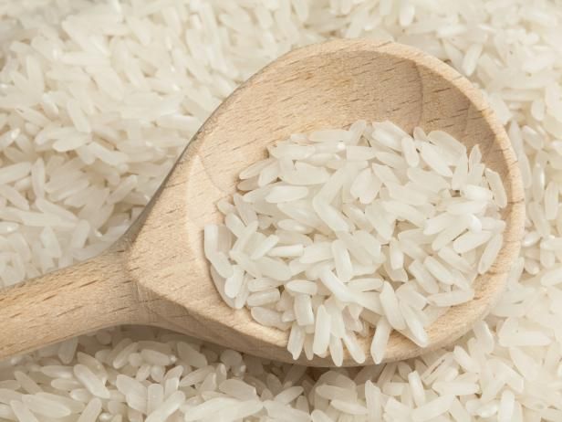 a wooden spoon filled with white rice on top of a table