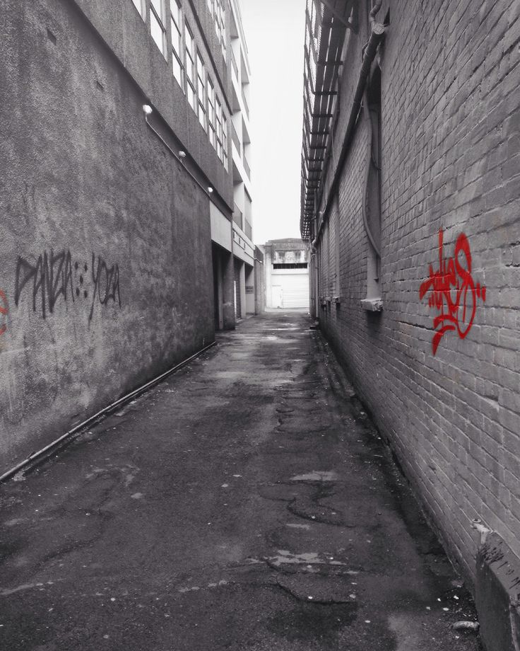 an alley way with graffiti on the wall and brick buildings in the backround