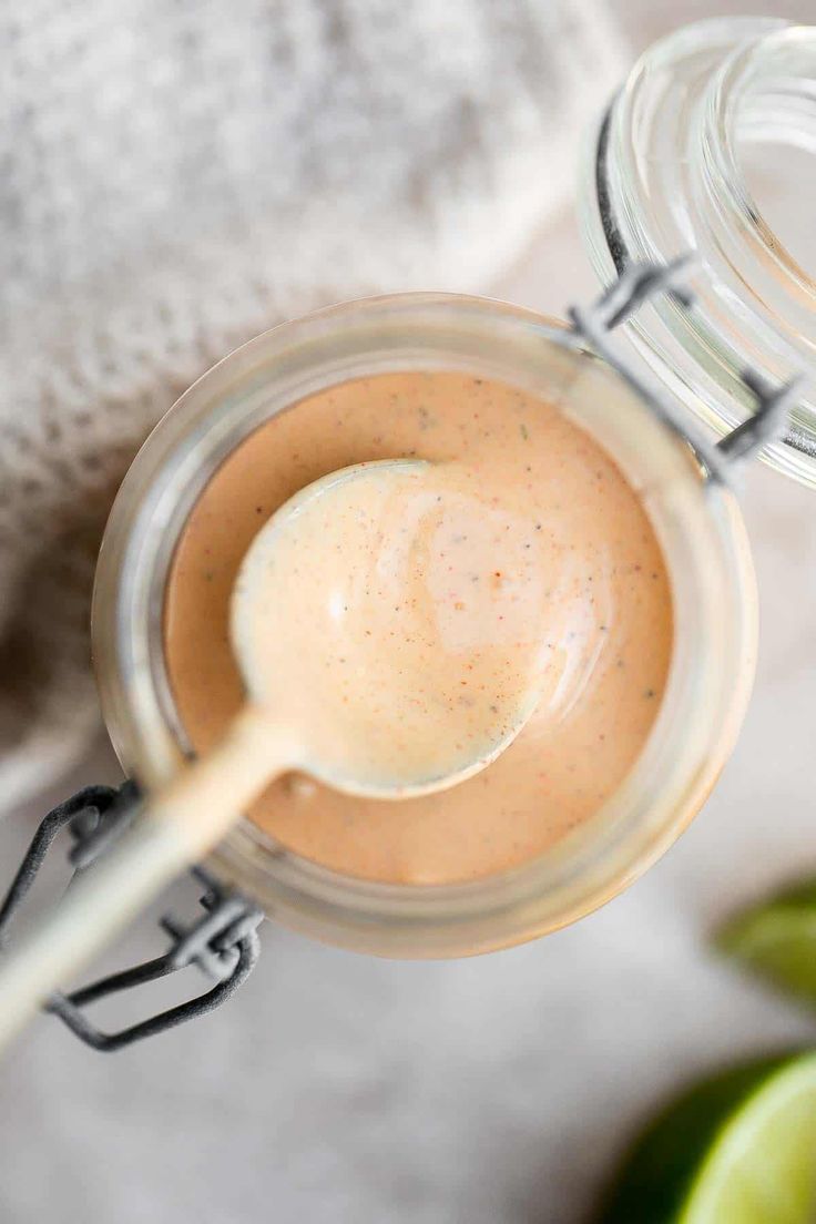 a glass jar filled with liquid next to an avocado