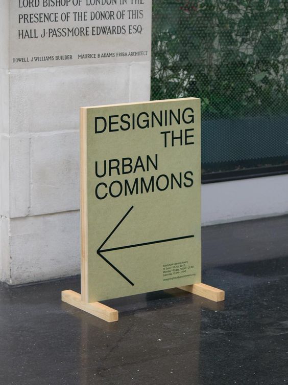 a sign that says designing the urban commonss in front of a building with an arrow on it