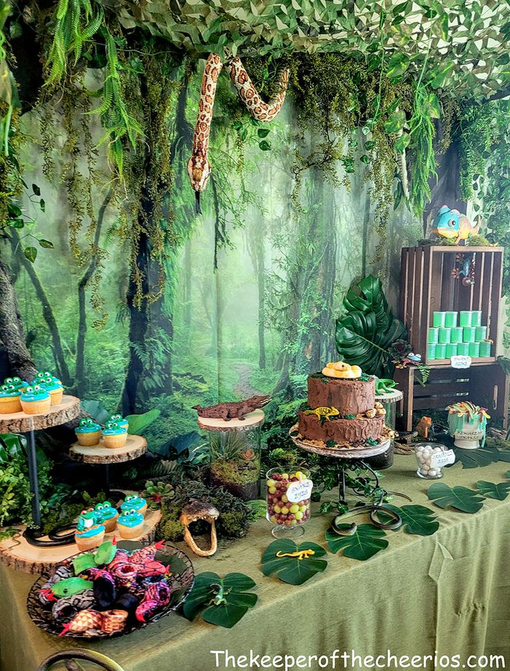 a jungle themed birthday party with cake and cupcakes on a table in front of a backdrop