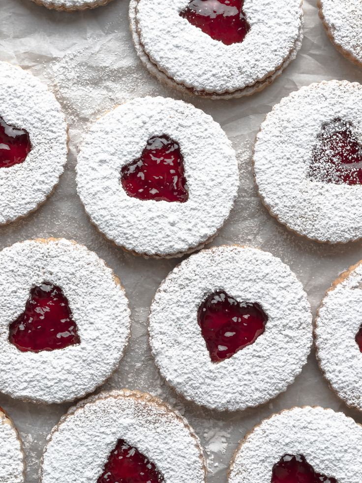 strawberry jam linzer cookies with powdered sugar in the shape of a heart on top