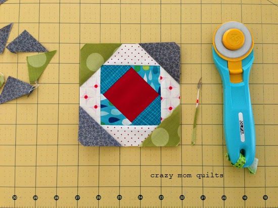 a pair of scissors sitting on top of a cutting board next to a patch of fabric