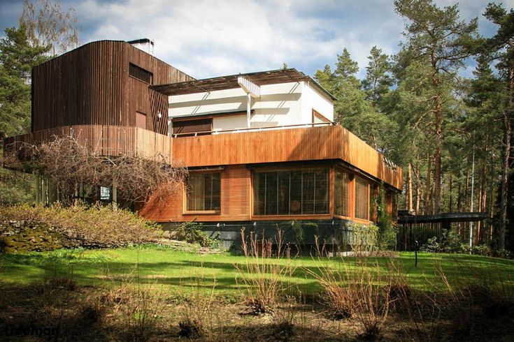 a house in the middle of a wooded area with tall trees and grass around it