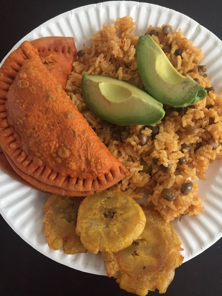 a white plate topped with rice and veggies next to an avocado