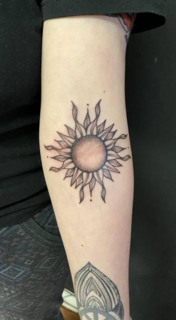 a woman's arm with a sun tattoo on the left side of her leg