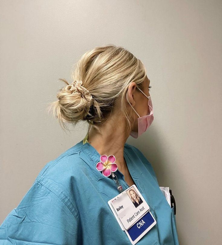 a woman in scrubs with a name tag on her neck and pink nosepiece