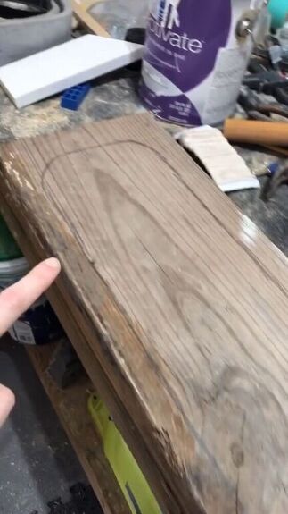 a hand pointing at a piece of wood that is being made into a table top