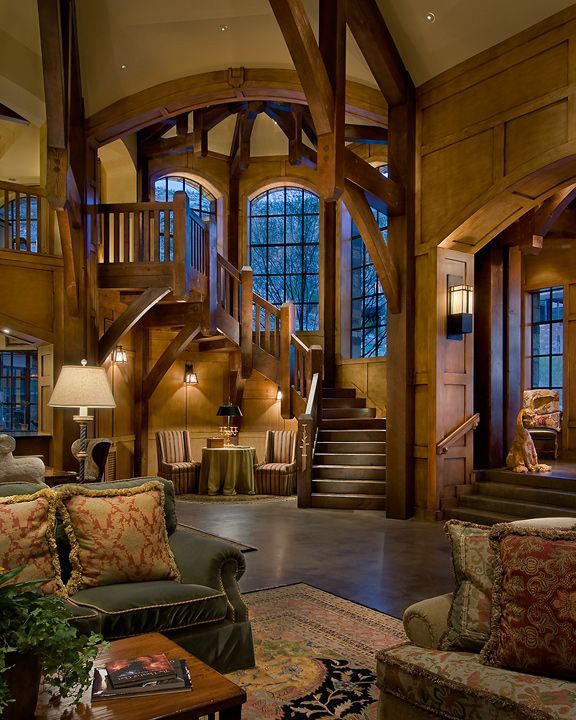 a living room filled with furniture and lots of woodwork on the walls next to a stair case