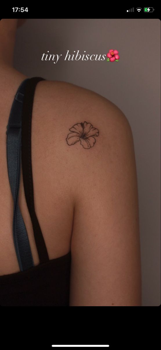 the back of a woman's shoulder with a flower tattoo on her left arm