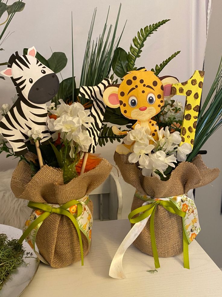 two vases filled with flowers and stuffed animals on top of a table next to each other