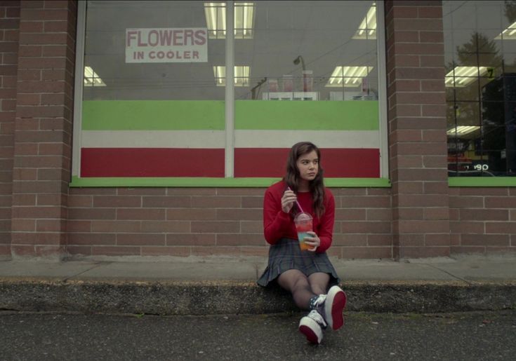 a woman sitting on the side of a road next to a building