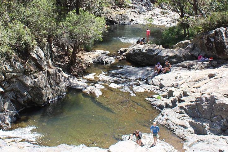 people are swimming in the river near some rocks