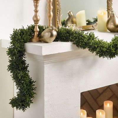 a mantle with candles and greenery around it in front of a mirror on the wall