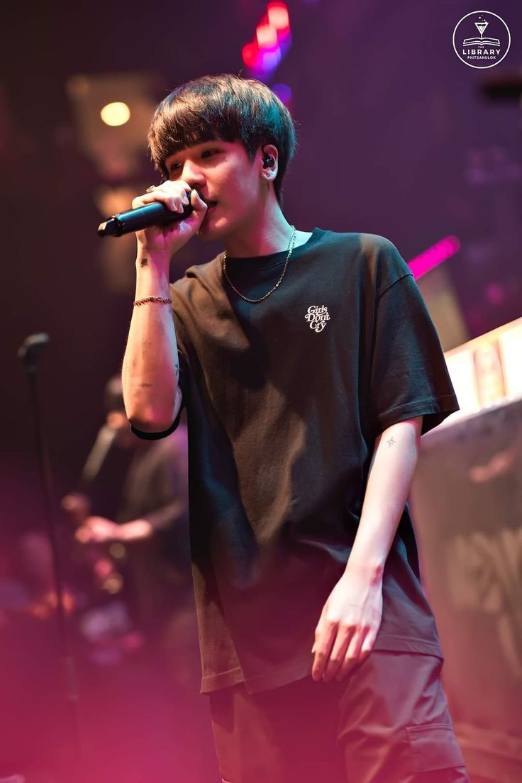 a young man singing into a microphone on stage