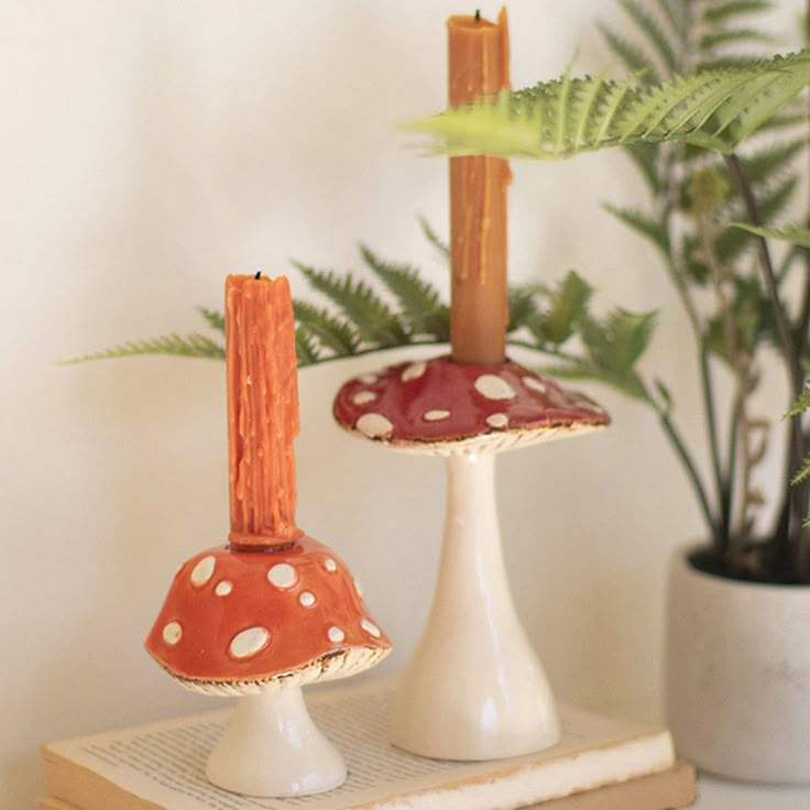 two small mushrooms sitting on top of a book next to a potted fern plant