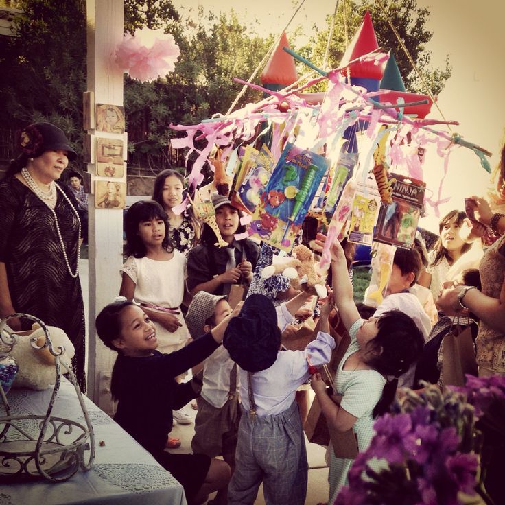 a group of people standing around each other near a table with balloons and streamers