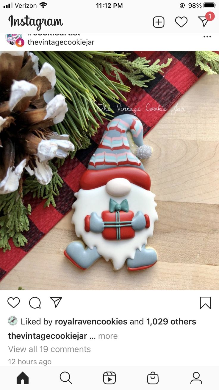 a cookie decorated like a santa clause sitting on top of a table next to pine cones