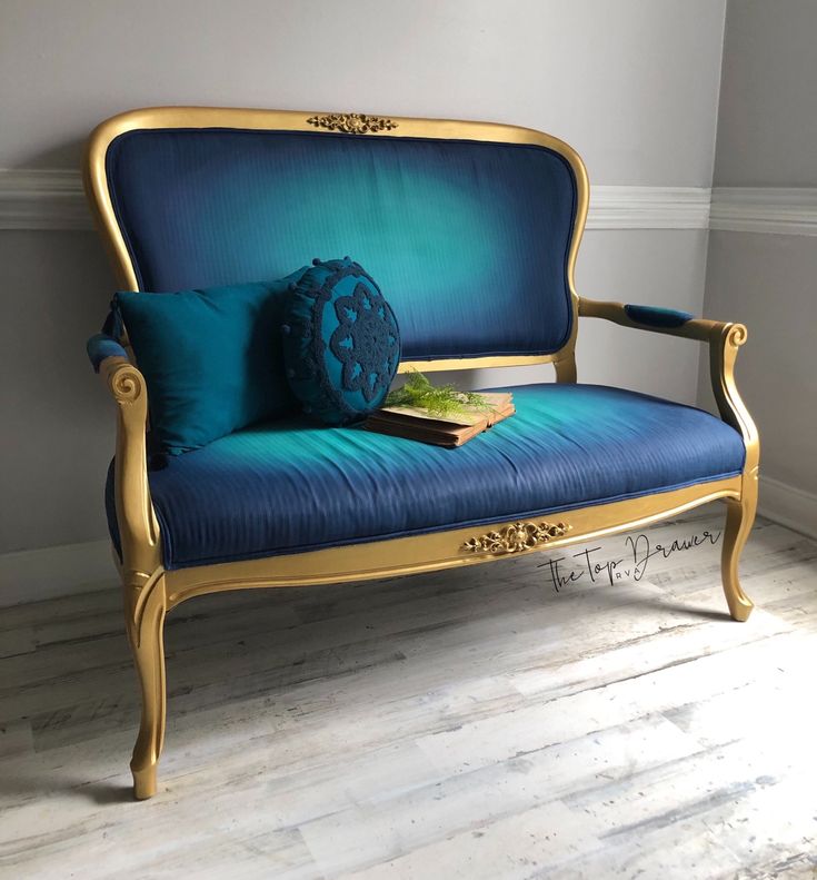 a blue couch sitting on top of a hard wood floor next to a white wall