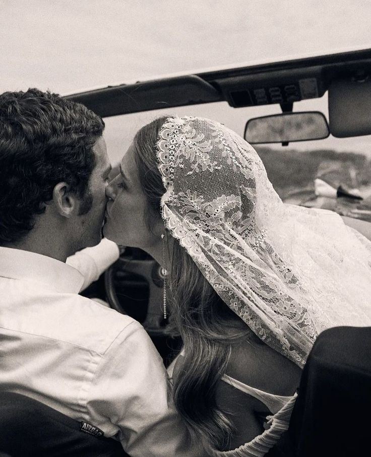 a bride and groom kissing in the back seat of a car