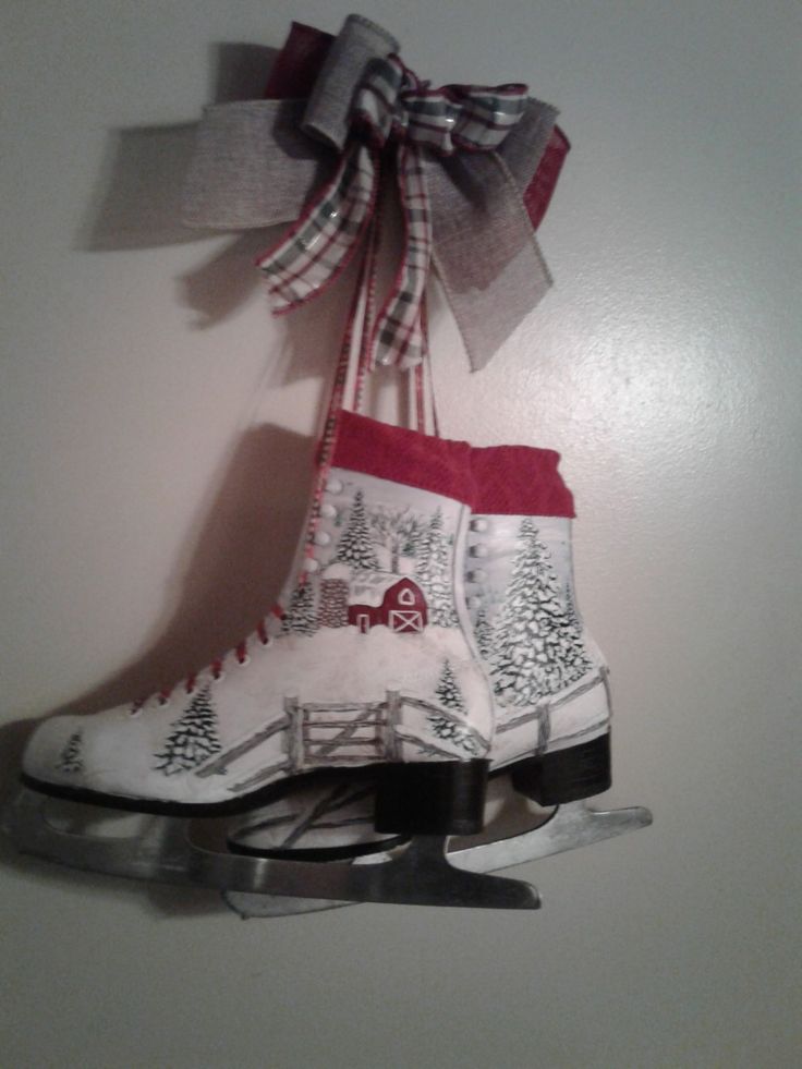 two pairs of ice skates hanging on the wall with ribbon and scissors attached to them