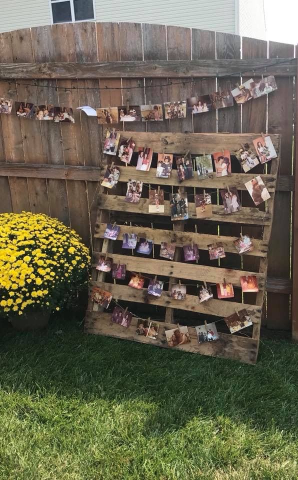 a wooden pallet with pictures on it and flowers in the yard next to it