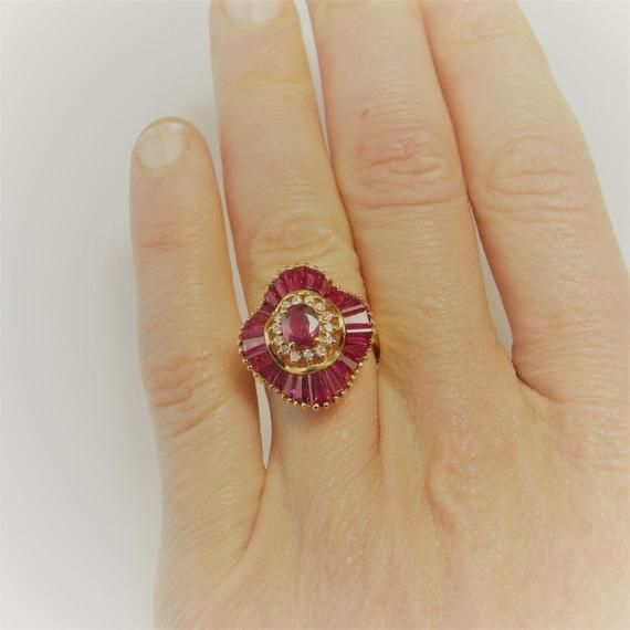 Here we have an exquisite vivid red ruby and diamond ballerina ring. The rubies here perfectly matched for color with astonishing intensity and clarity. The central ruby alone measures approximately 5.82mm x 3.80mm x 2.63mm weighing  0.65 carats. Additionally the ruby accents which are tapered baguettes weigh approximately 3.12 carats. These amazing accent rubies are arranged in a sensuous undulating circle surrounding the beautiful central red ruby. There are 13 points of VS/SI clarity G/H colo Luxury Red Ruby Ring Baguette Cut, Luxury Red Baguette Cut Ruby Ring, Red Baguette Cut Ruby Ring, Red Ruby Ring With Baguette Cut Center Stone, Elegant Ruby Ring With Baguette Cut, Red Diamond Baguette Cut Rings, Red Baguette Cut Lab-created Ruby Ring, Fine Jewelry Red Baguette Cut Ruby Ring, Red Hallmarked Cluster Ring