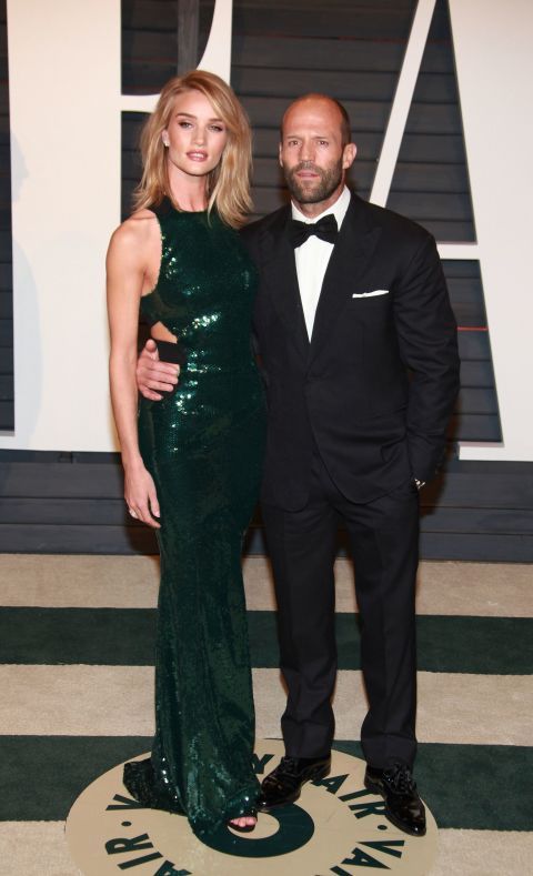 a man in a tuxedo standing next to a woman in a green dress