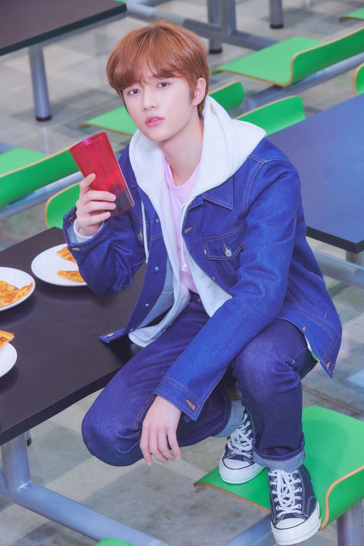 a young man sitting at a table holding a cell phone