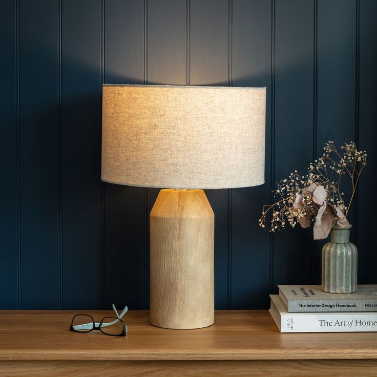 a table lamp sitting on top of a wooden table next to a pair of glasses