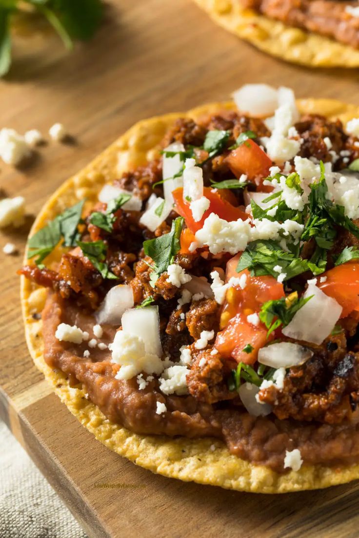 four small pita breads topped with black beans, cheese and cilantro