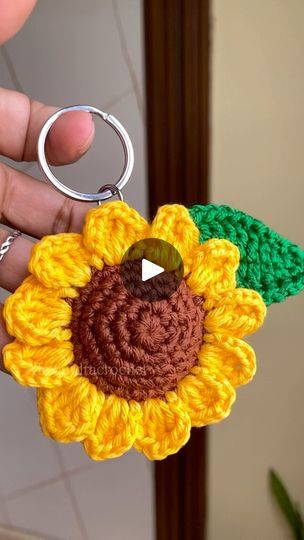 a crocheted keychain with a sunflower on it is being held by someone's hand