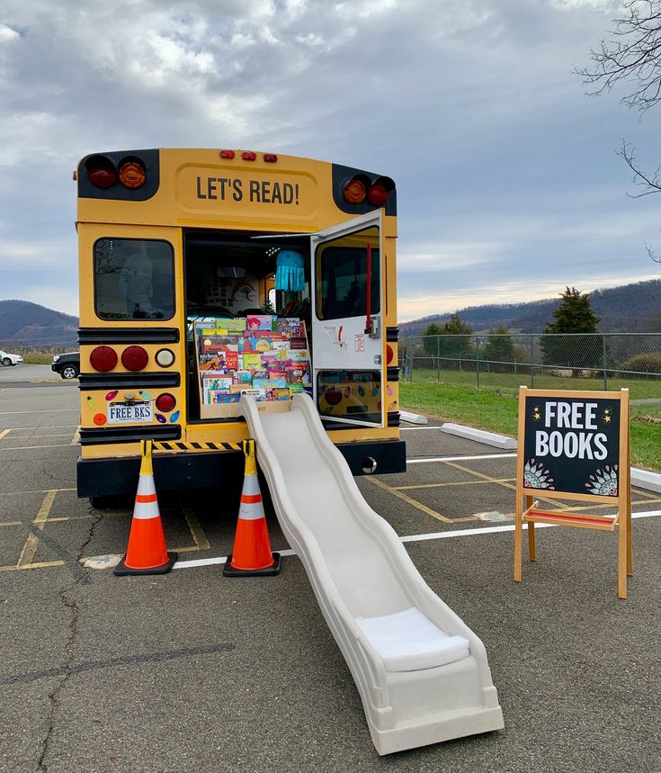 a school bus parked in a parking lot with a slide next to it and a sign that says let's read