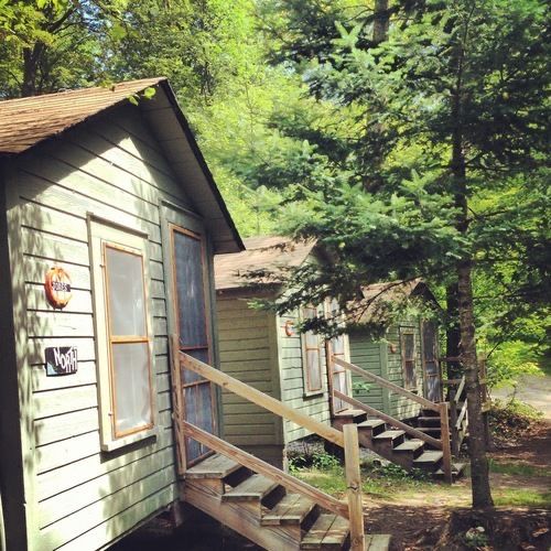 a small cabin in the woods with stairs leading up to it