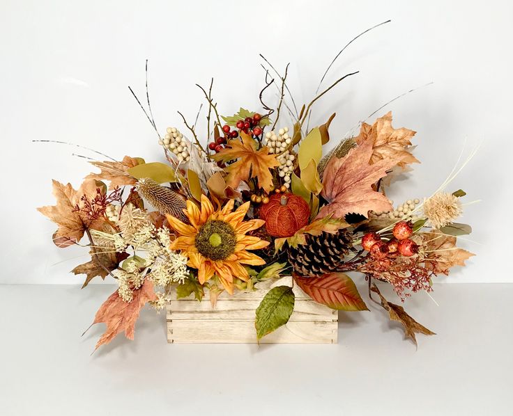 a wooden box filled with lots of different types of fall leaves and flowers on top of a table