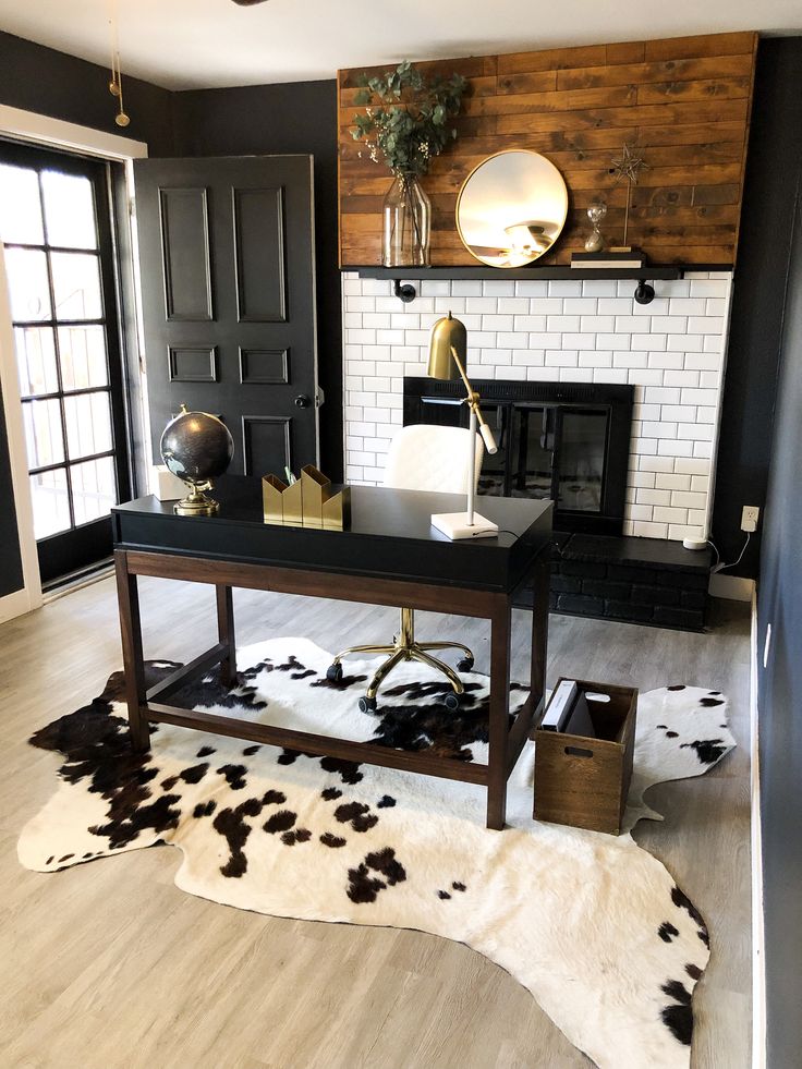 a black and white cow hide rug in the middle of a room with a fireplace