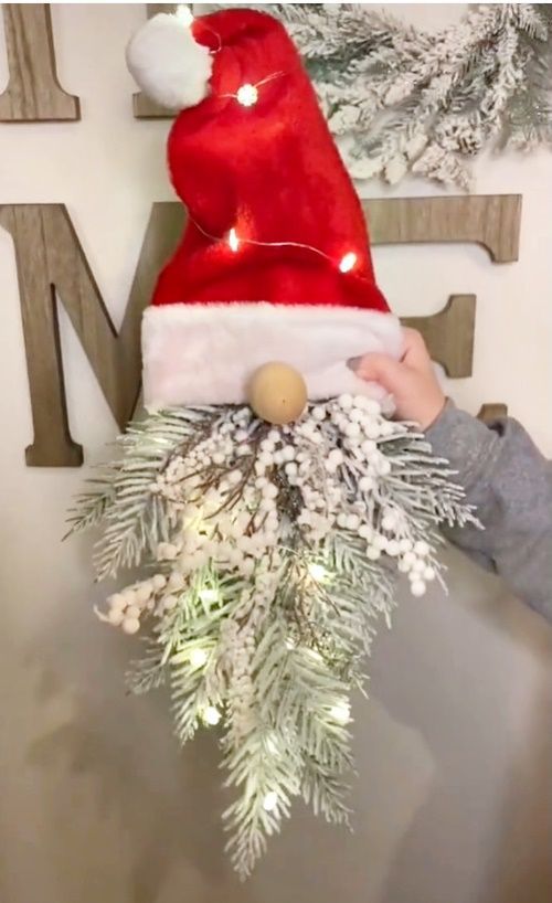 a child is holding a christmas wreath with lights on it and wearing a santa hat