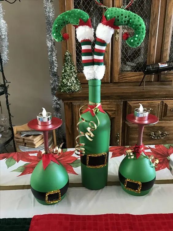 two green christmas wine bottles with santa hats and stockings hanging from them on a table