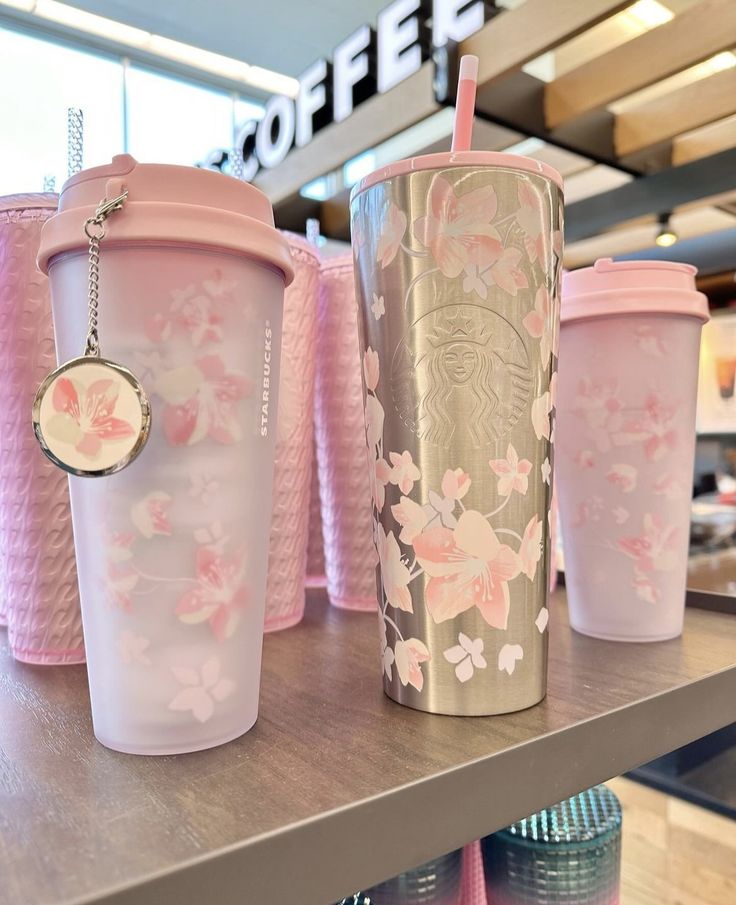 three pink starbucks cups sitting on top of a shelf next to each other in a store