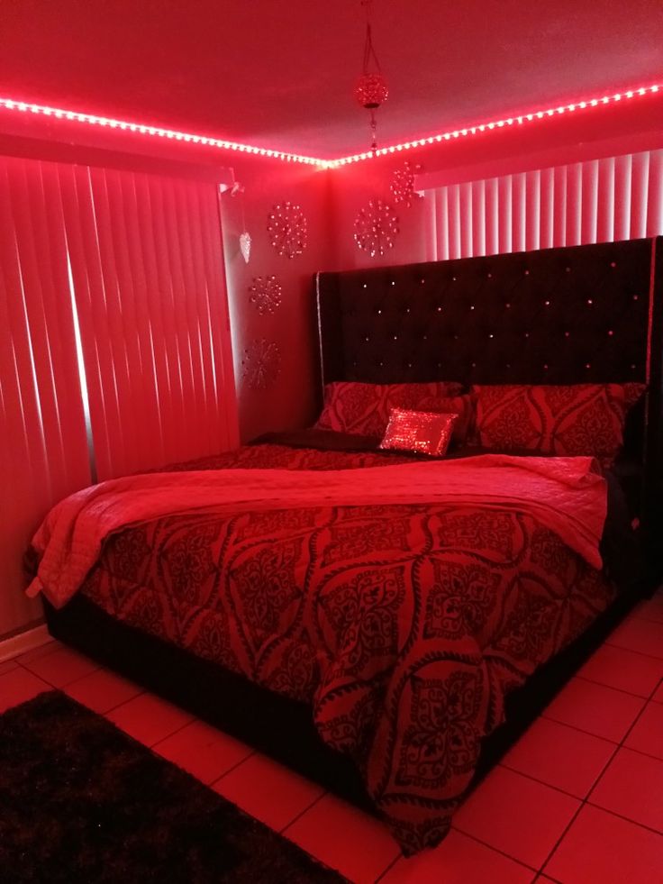 a bed in a room with red lights on the headboard and foot board,