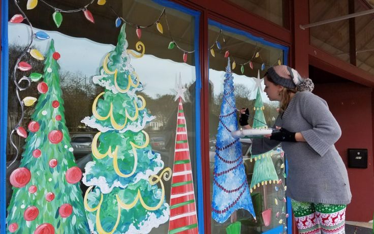 a woman standing in front of a window decorated with christmas decorations