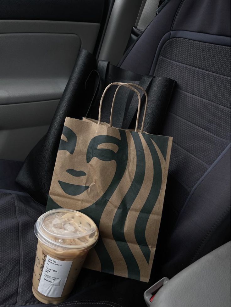 a starbucks bag sitting on the back seat of a car next to a cup of coffee