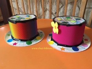 two colorful hats sitting on top of a table next to each other, one with a butterfly on it