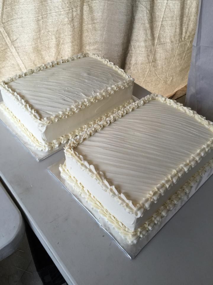 two square cakes sitting on top of a white table next to each other in front of a curtain