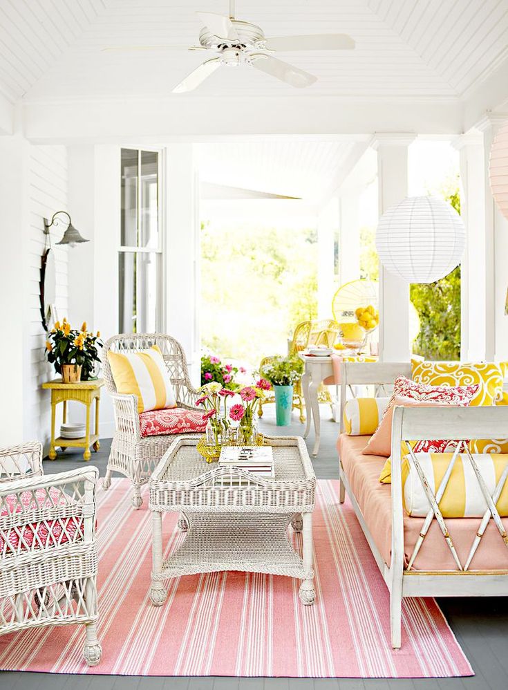 a living room filled with lots of furniture and flowers on top of a rug in front of a window