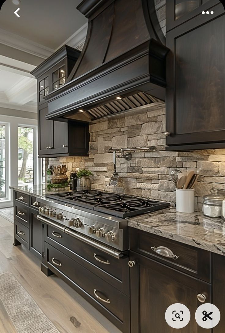 a kitchen with black cabinets and marble counter tops