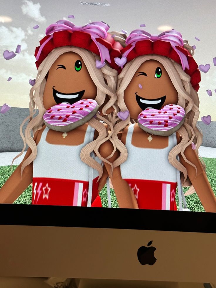 two girls with donuts on their faces in front of a computer screen